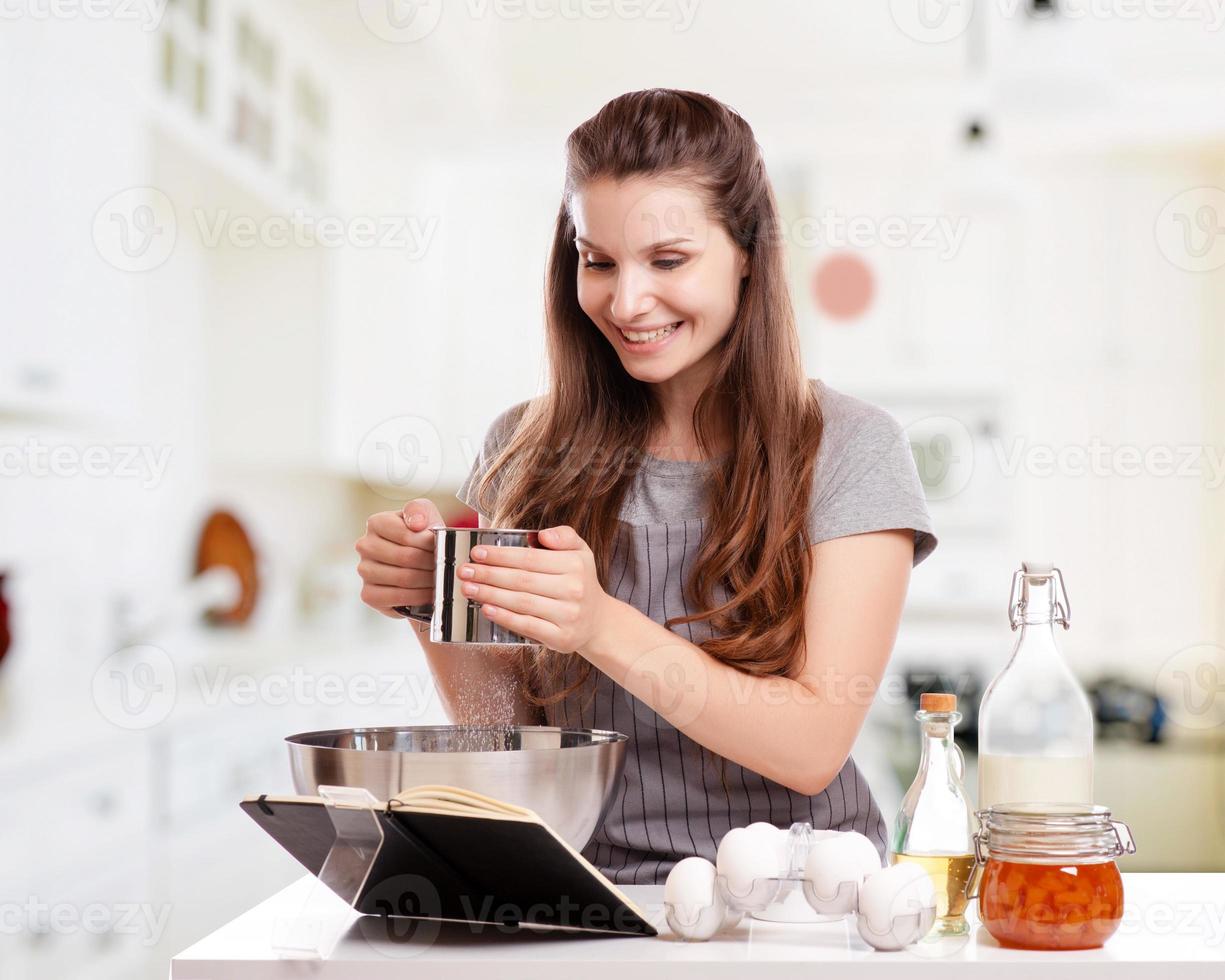 donna che cucina a casa seguendo la ricetta foto