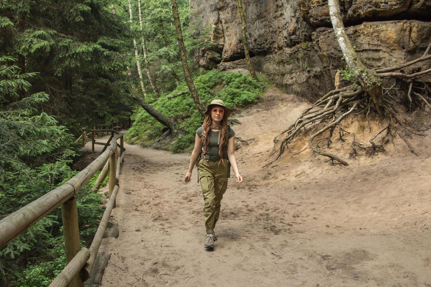 giovane donna che fa un'escursione sul prato di primavera, sulle montagne e sulla foresta sullo sfondo foto