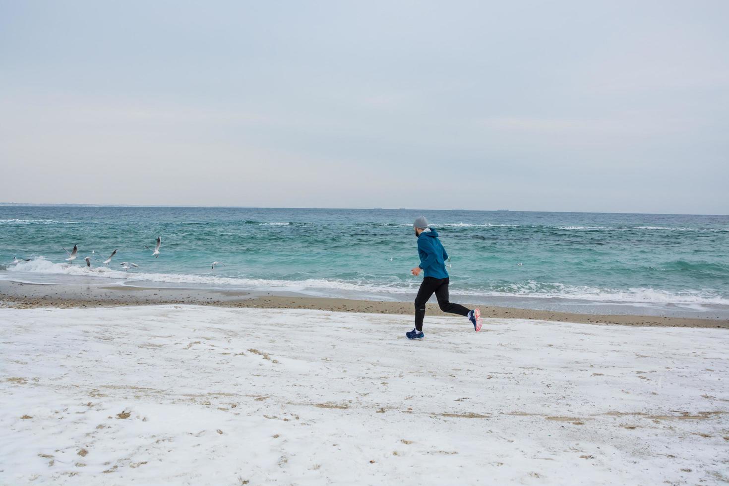 giovane corridore maschio che si allena all'aperto nei periodi invernali, l'uomo corre sulla neve foto