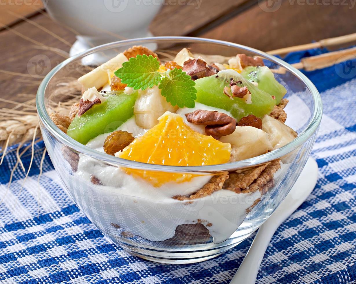 dessert sano con muesli e frutta in una ciotola di vetro sul tavolo foto