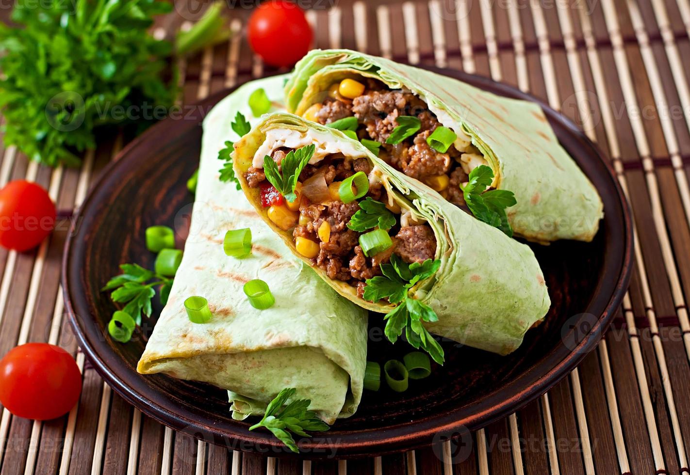 burritos avvolge con carne macinata di manzo e verdure su un fondo di legno foto