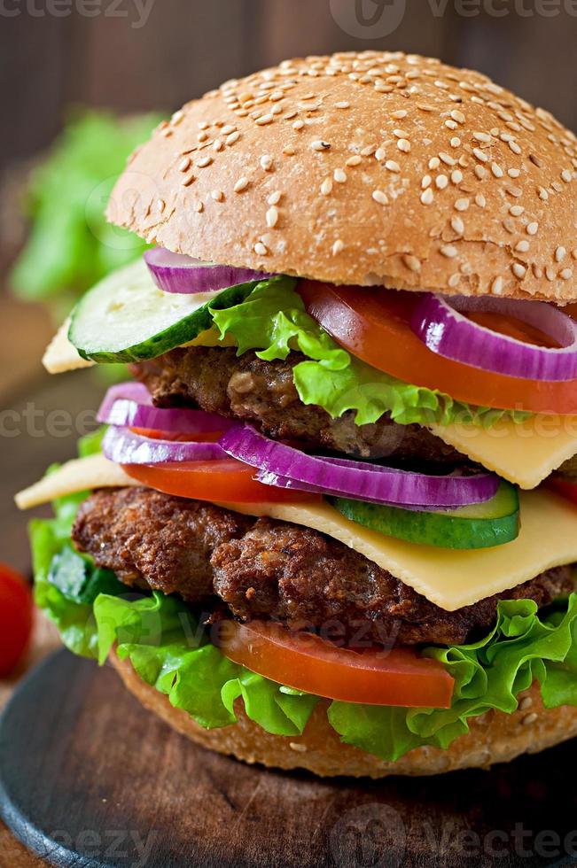 grande succoso hamburger con verdure e carne su uno sfondo di legno in stile rustico foto