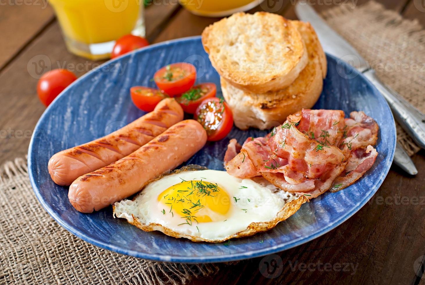 colazione all'inglese - pane tostato, uova, pancetta e verdure in stile rustico su fondo di legno foto