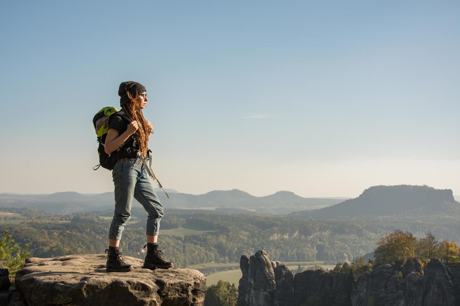 giovane donna viaggiatore con baclpack stand sulla scogliera in montagna foto