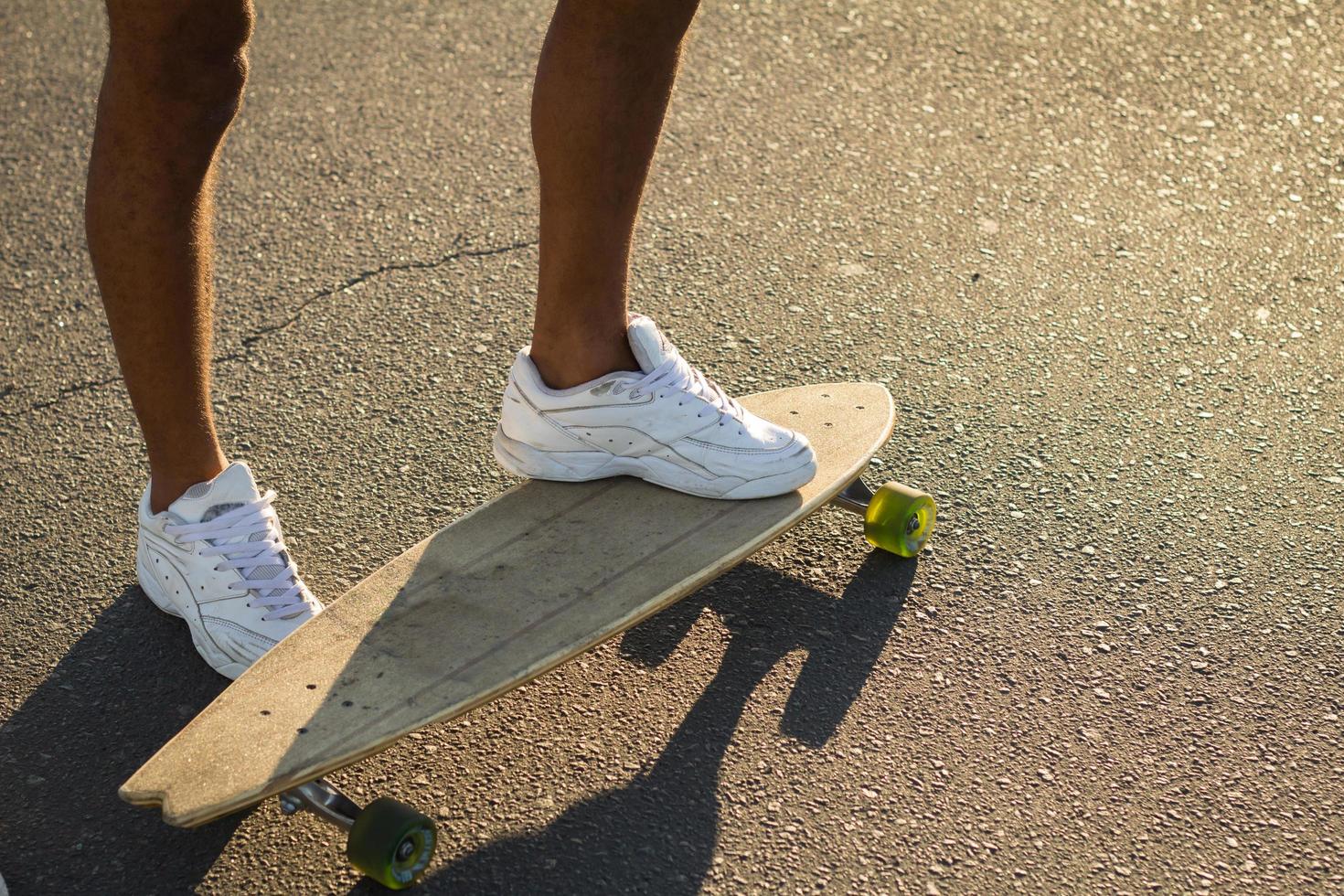 longboard skate stand alone su asfalto alla luce del sole gialla foto