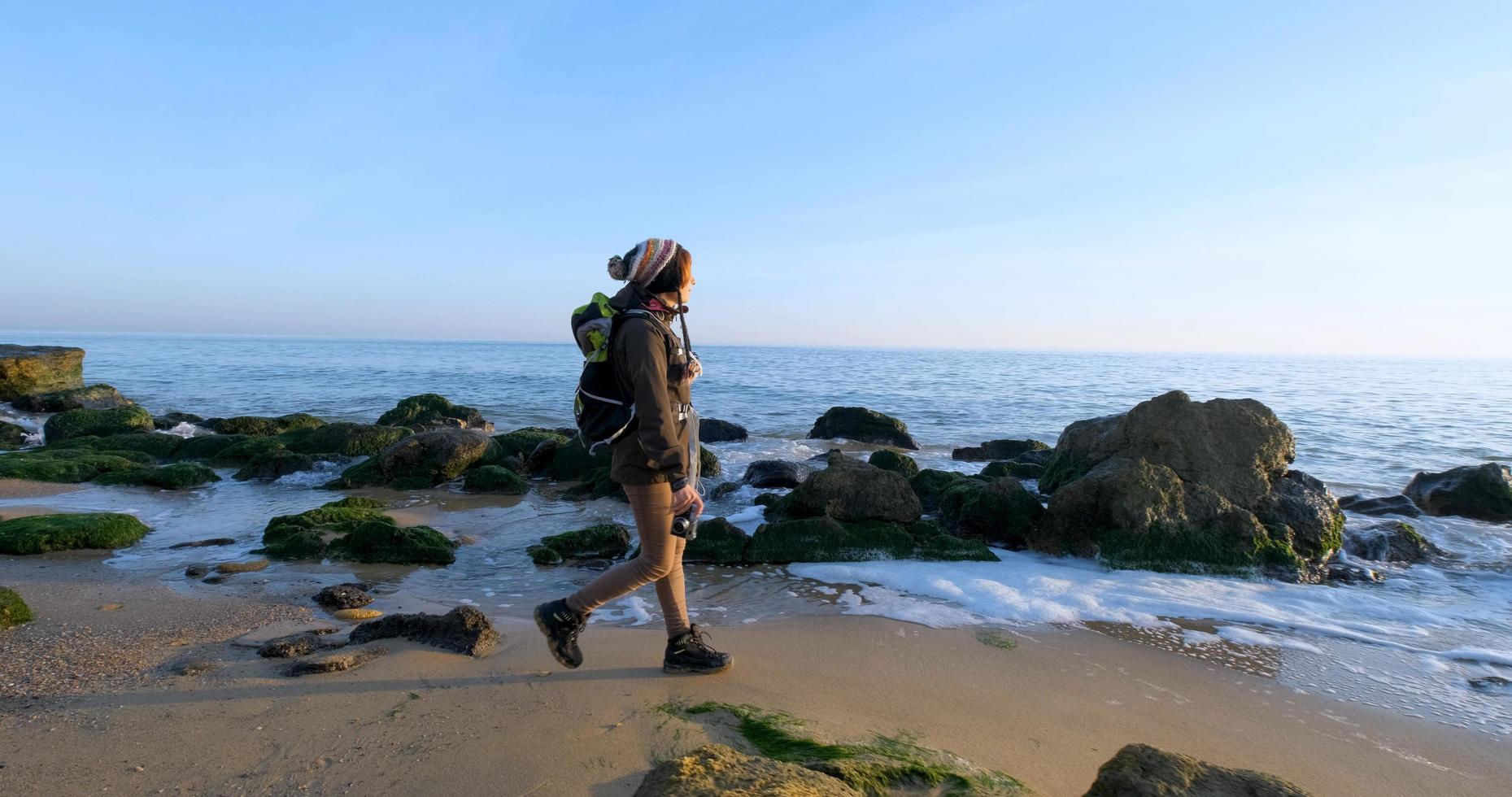 giovane viaggiatore femminile con zaino e fotocamera a pellicola retrò viaggia nelle montagne autunnali vicino al mare foto