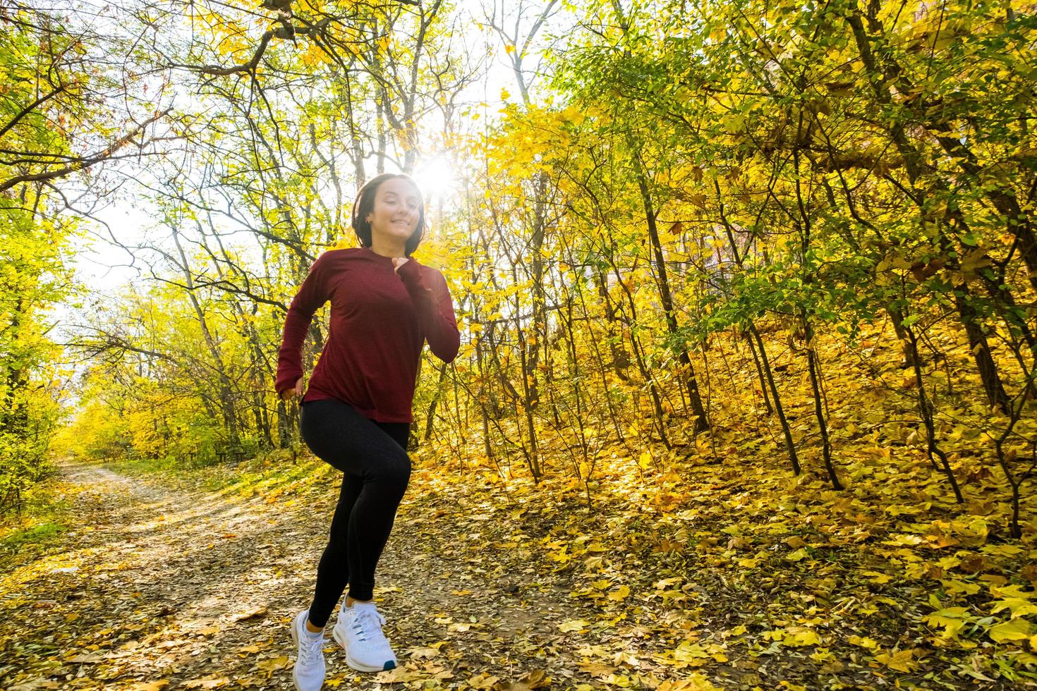 giovane donna felice corridore formazione nel soleggiato parco autunnale foto