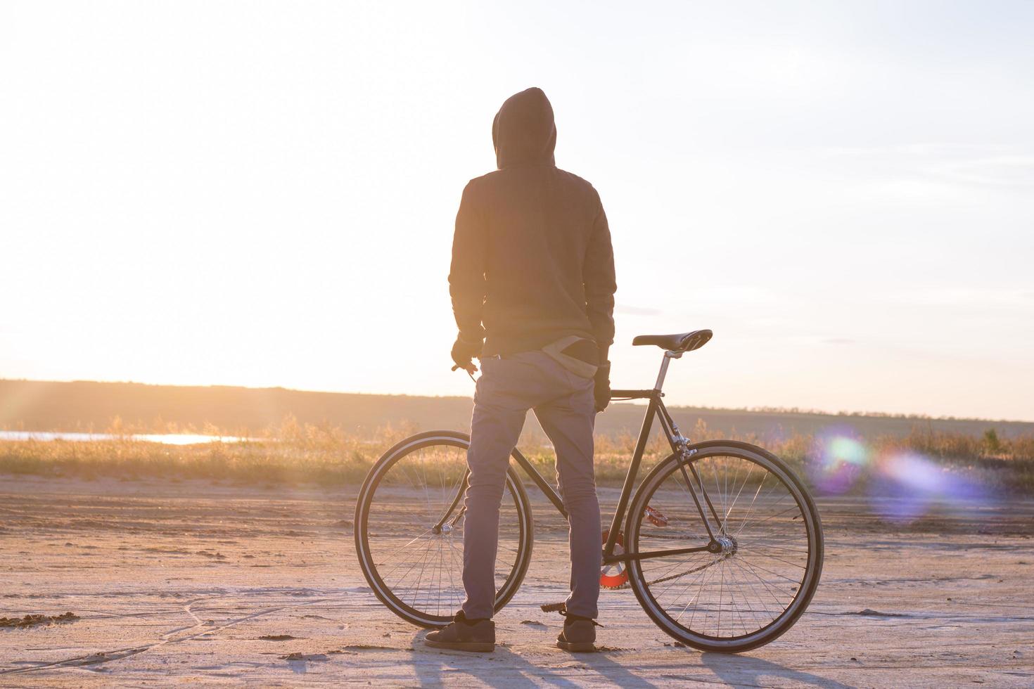 pilota da solo su bici da strada a scatto fisso che guida nel deserto vicino al fiume, foto di ciclista turistico hipster.