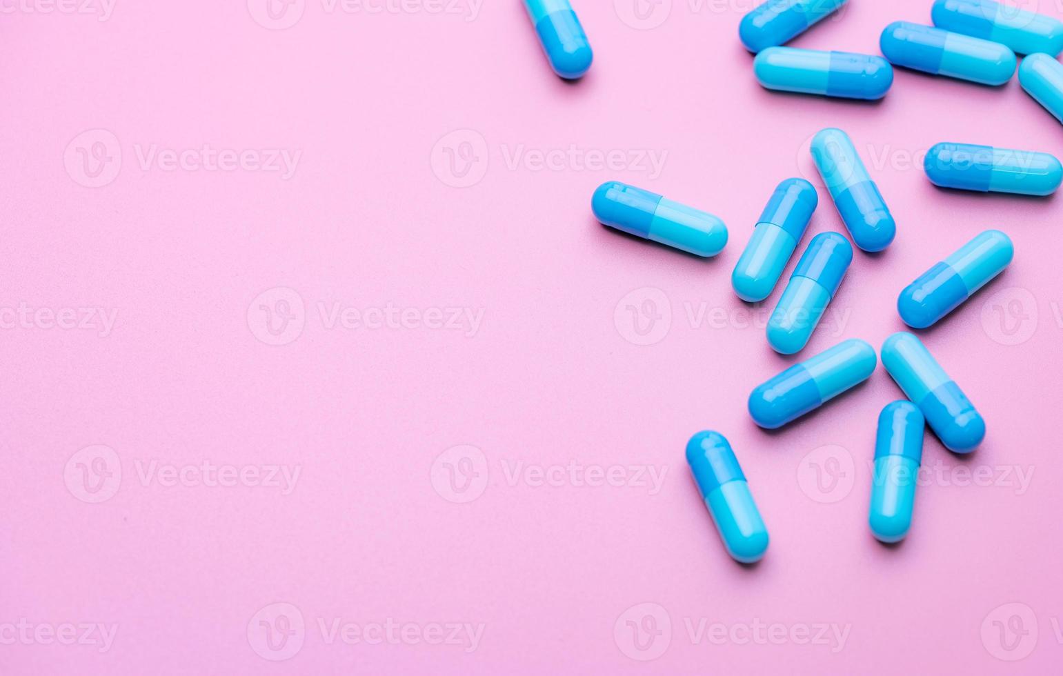 capsule blu su sfondo rosa. pillole blu della capsula con lo spazio della copia. industria farmaceutica. prodotto della farmacia comunitaria. uso di droghe in gravidanza argomenti relativi alla donna e all'allattamento e agli anziani. foto