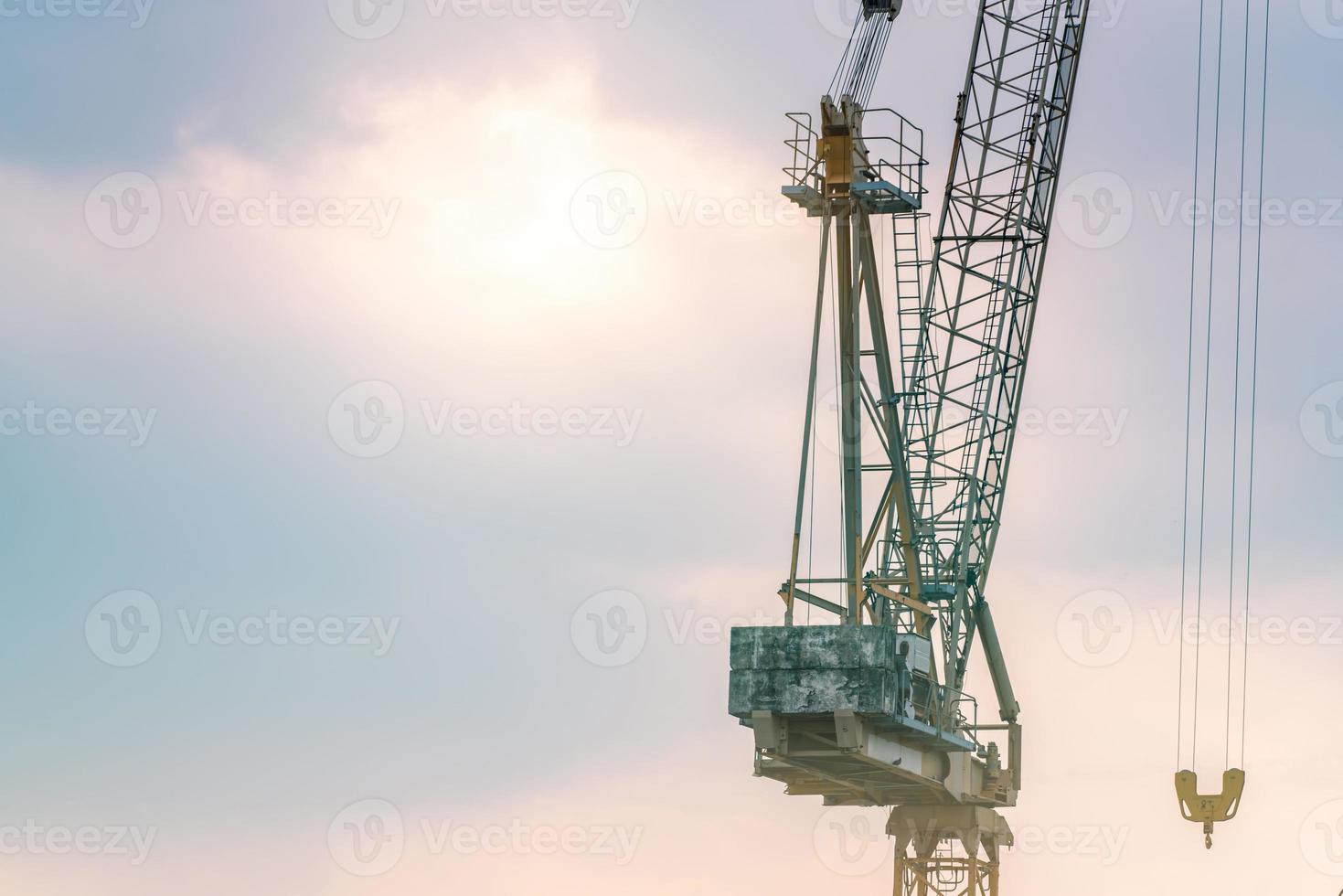 gru da costruzione contro il cielo blu e rosa. settore immobiliare. gru edile utilizzare bobina di sollevamento attrezzature in cantiere. gru in affitto. concessionaria di gru per attività di costruzione. foto