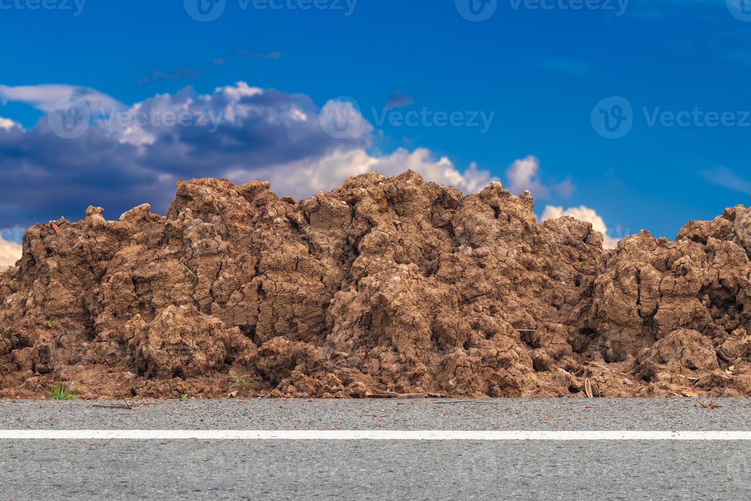 un mucchio di terreno accanto alla strada con nuvole sullo sfondo del cielo. foto