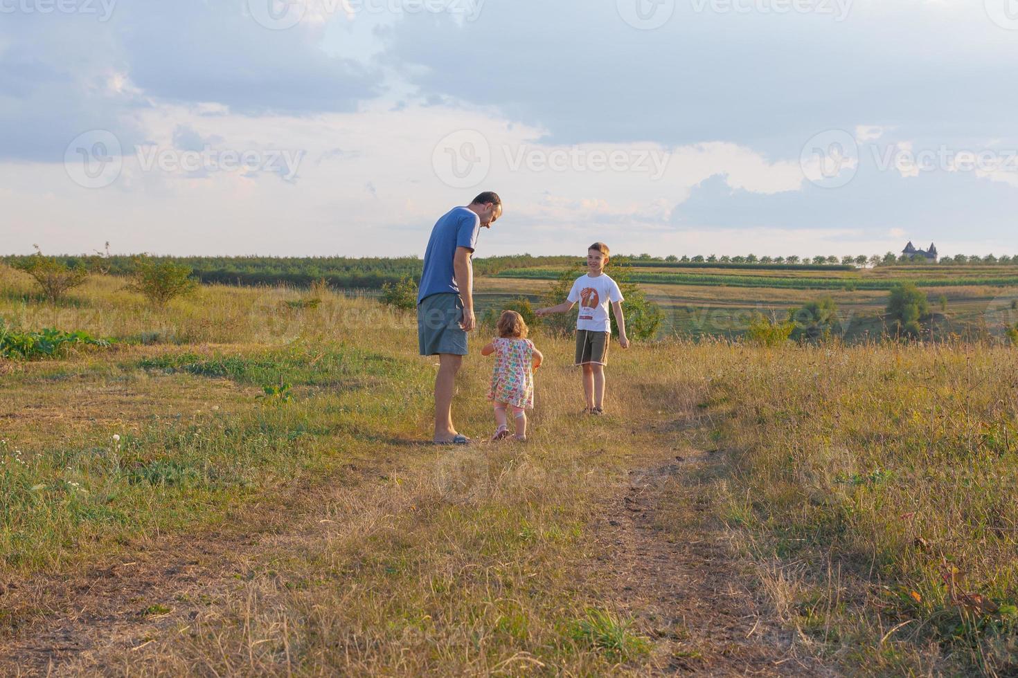 padre con figli sulle spalle in giardino. famiglia in natura nel concetto di villaggio foto