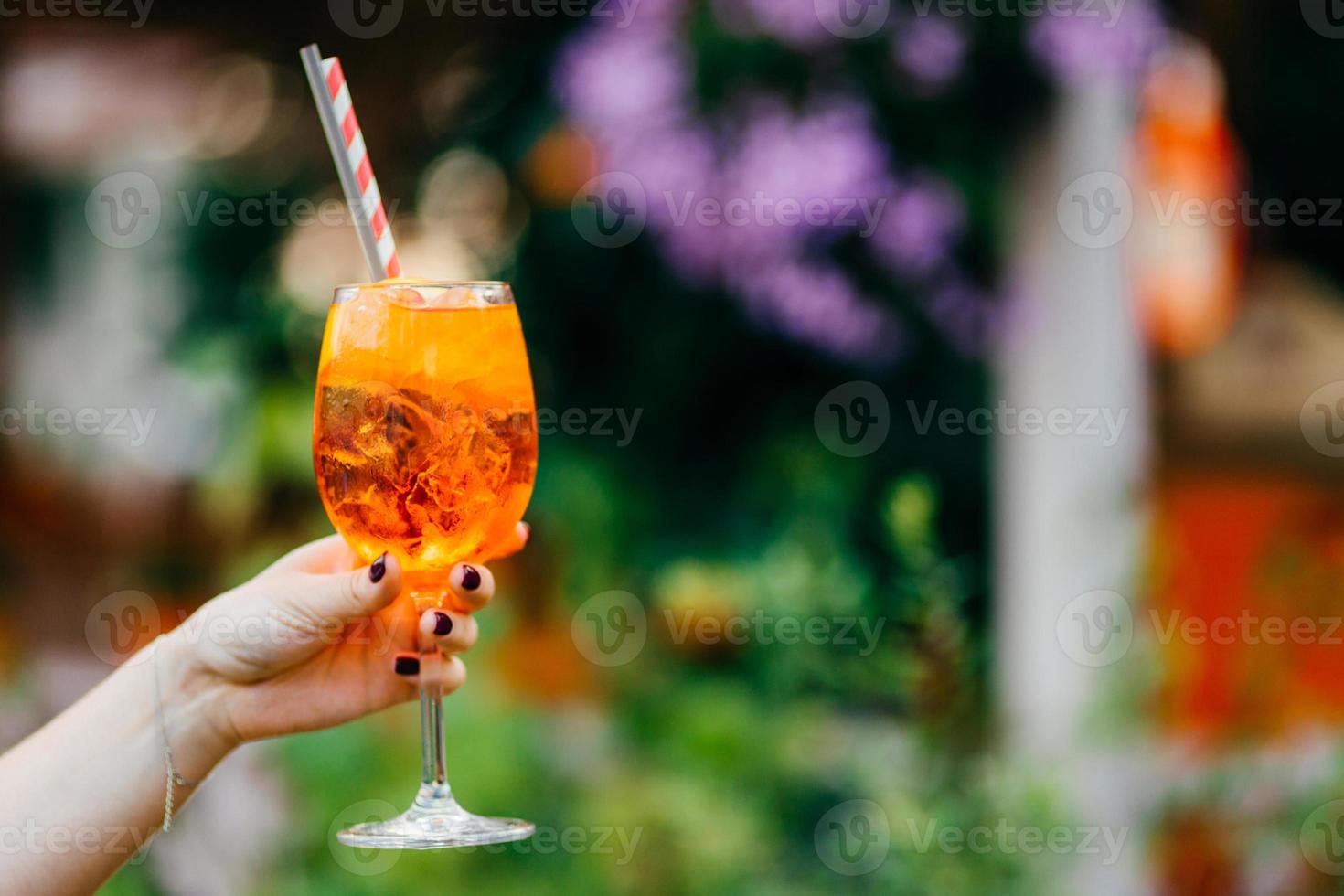 scatto all'aperto di cocktail fresco con ghiaccio nelle mani della donna su sfondo sfocato con spazio per la copia per il contenuto pubblicitario. bevanda fredda per la festa estiva foto