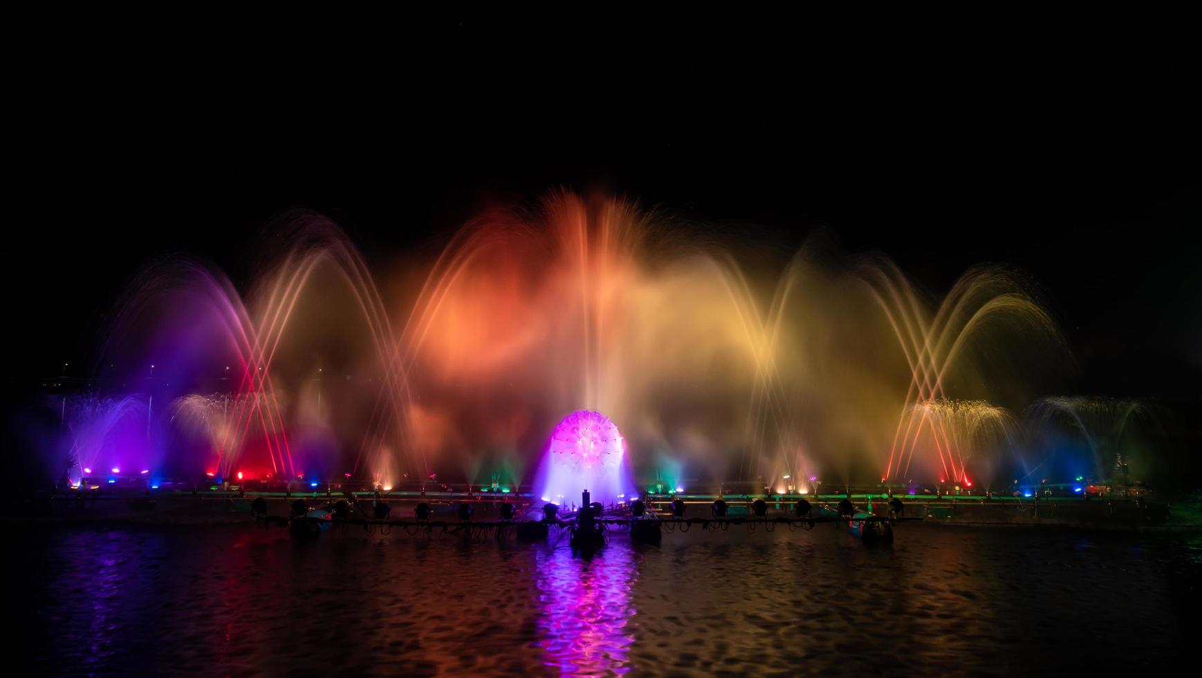 la fontana colorata che balla per celebrare l'anno con sfondo scuro del cielo notturno. foto