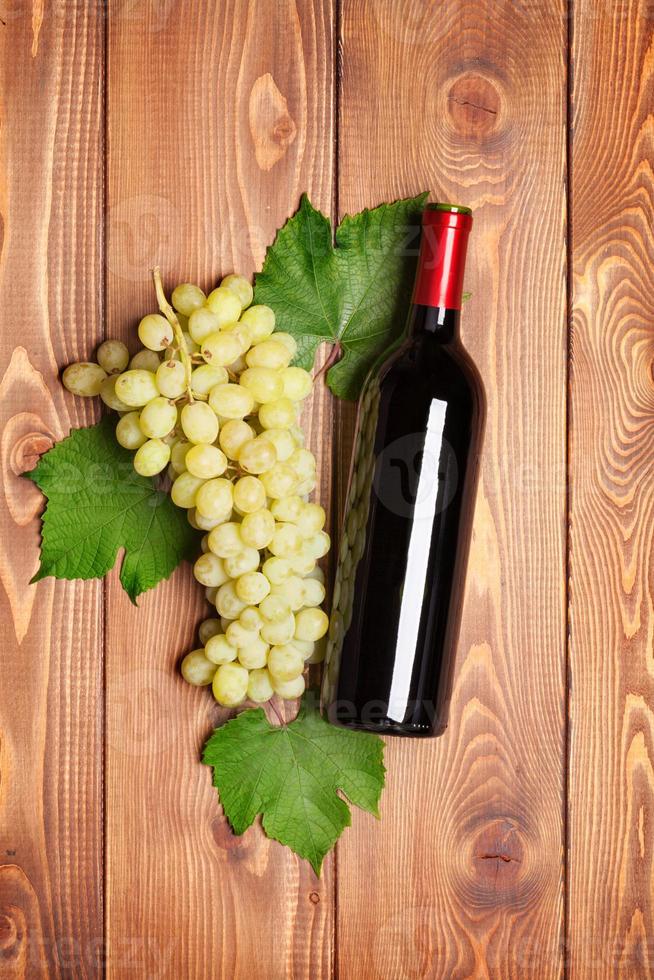 bottiglia di vino rosso e grappolo d'uva bianca foto