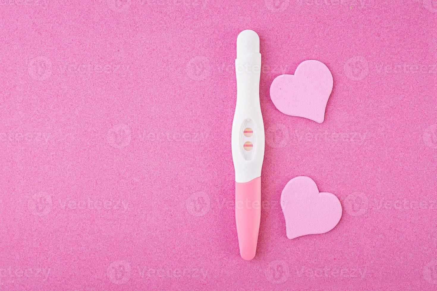 test di gravidanza positivo con cuori isolati su sfondo rosa foto