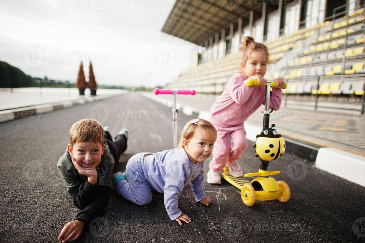 i bambini sull'asfalto giocano e si divertono. la famiglia sportiva trascorre il tempo libero all'aria aperta con scooter e pattini. foto