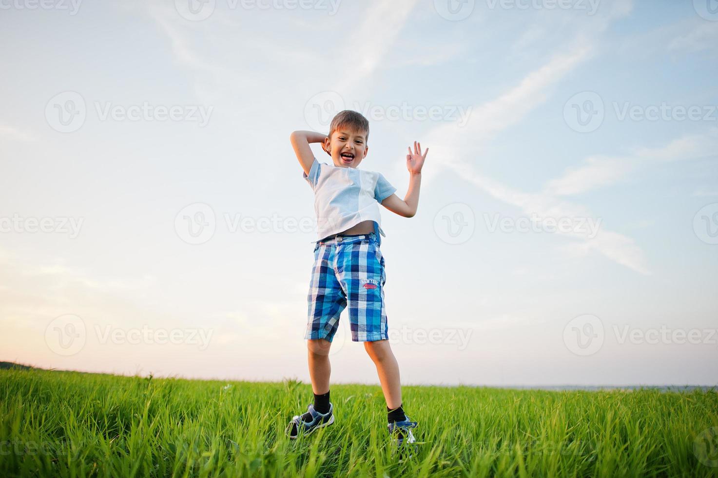 ragazzo carino che salta nel campo di erba verde alla sera. foto