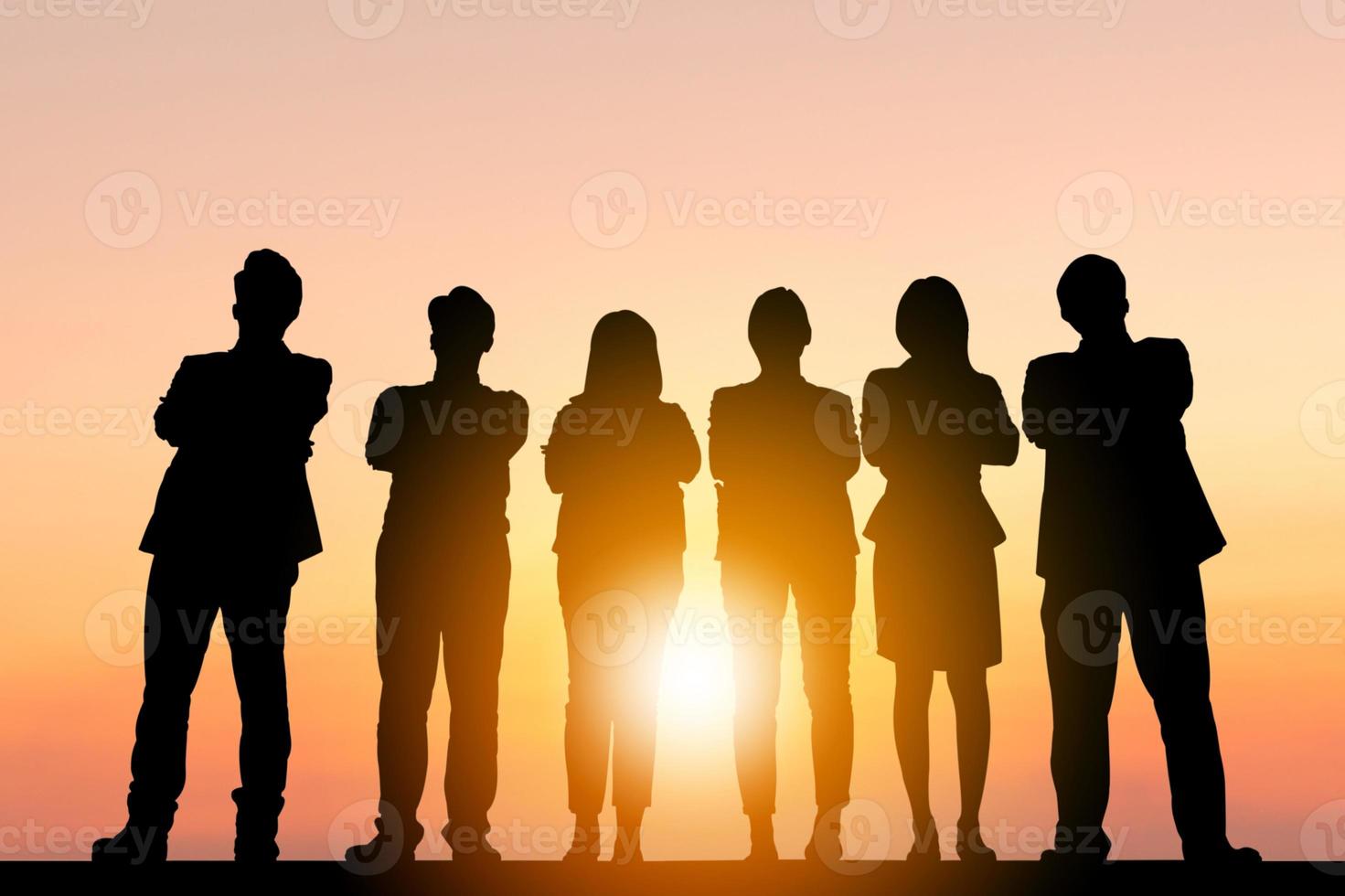 silhouette di uomini d'affari celebrazione successo felicità squadra in piedi con le braccia incrociate al tramonto sullo sfondo del cielo di sera foto