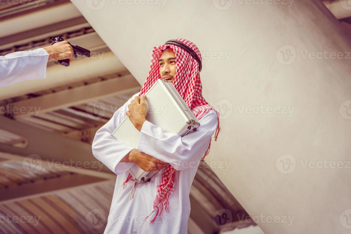 i ladri usano una pistola per rapinare una borsa da un uomo d'affari arabo mediorientale nella città, concetto criminale e di rapina. foto