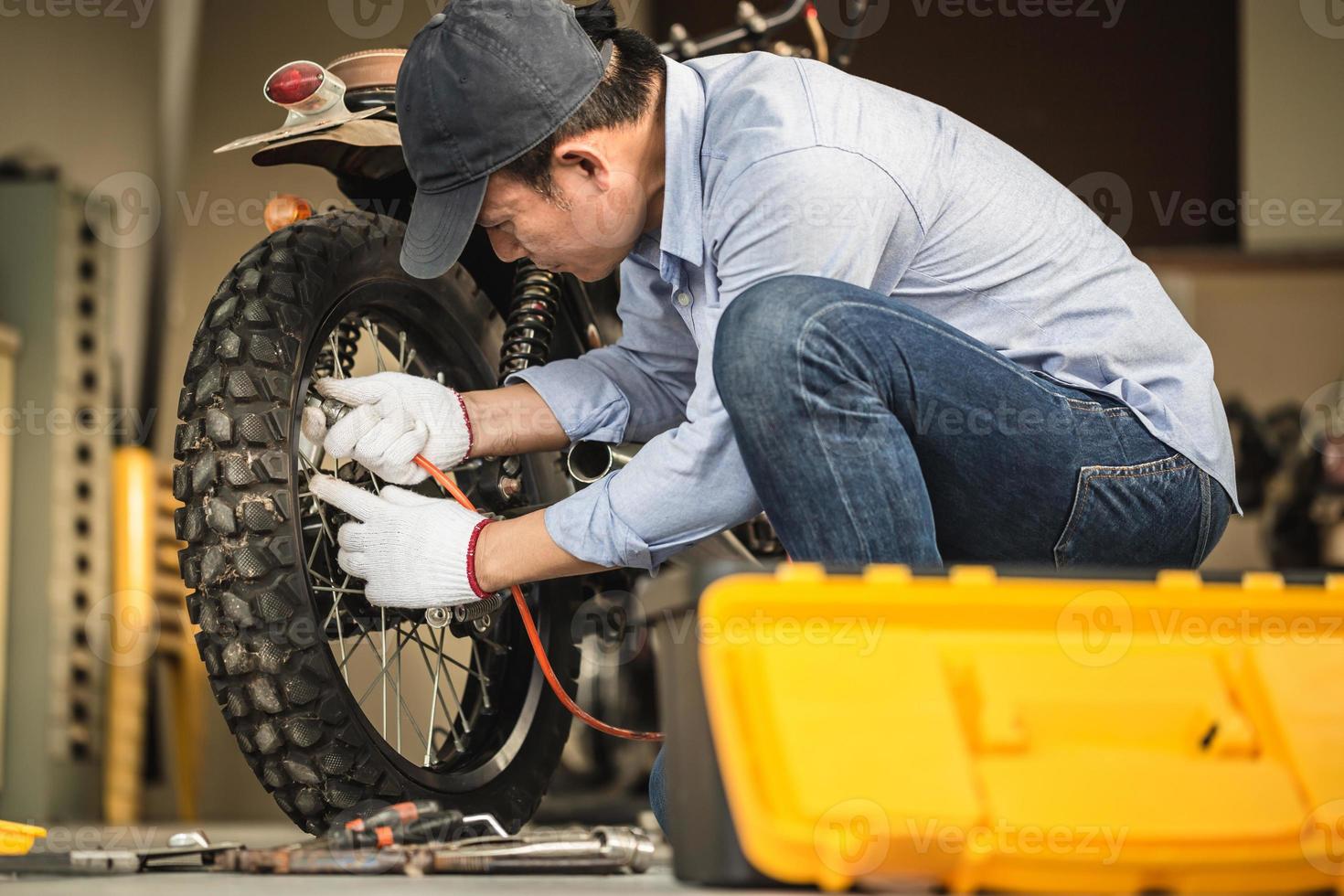 meccanico che ripara la moto nel garage dell'officina, uomo che ripara la motocicletta in officina, concetti di riparazione e manutenzione foto