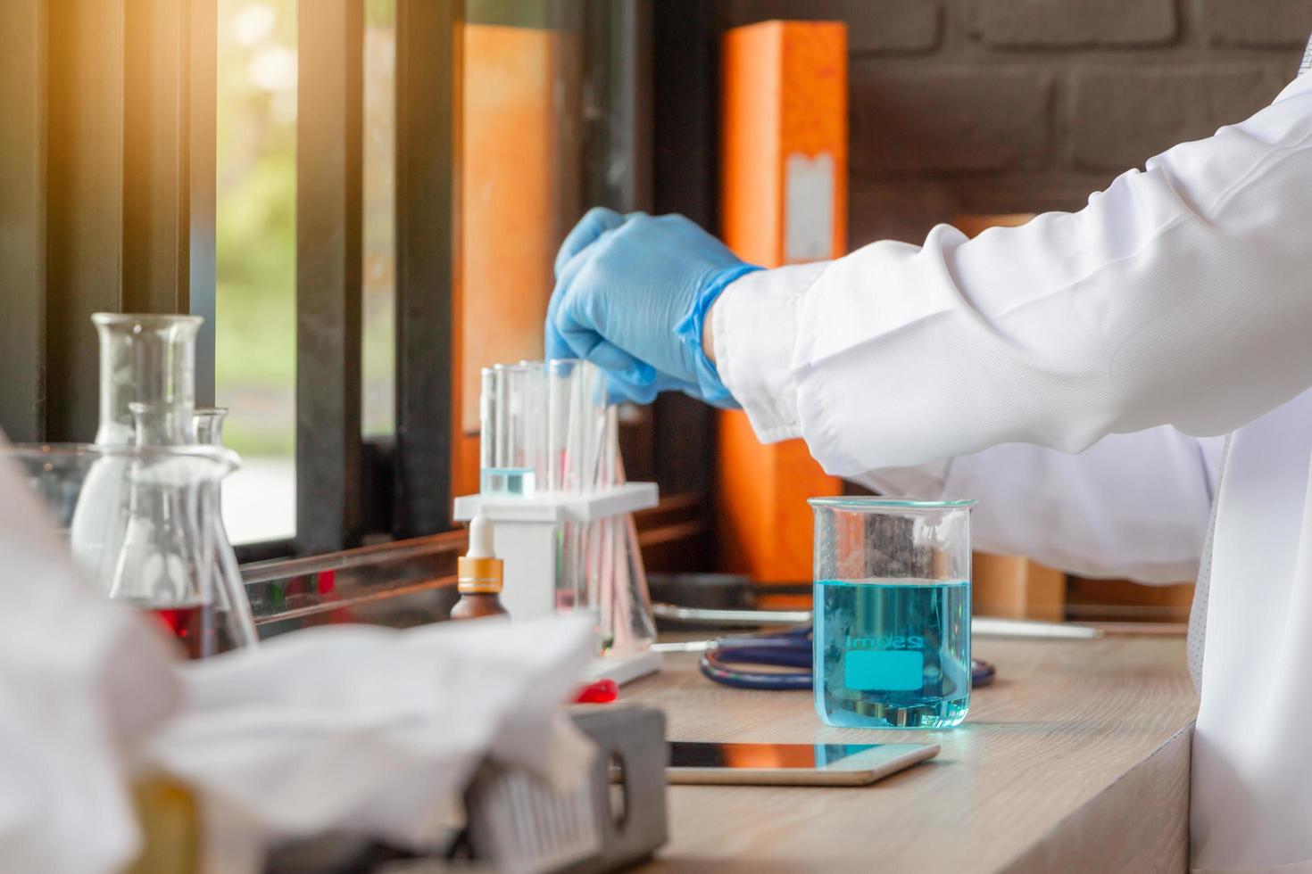 medico che analizza le provette mediche che esaminano il becher con fluido, scienziato che ricerca e apprende in un laboratorio foto