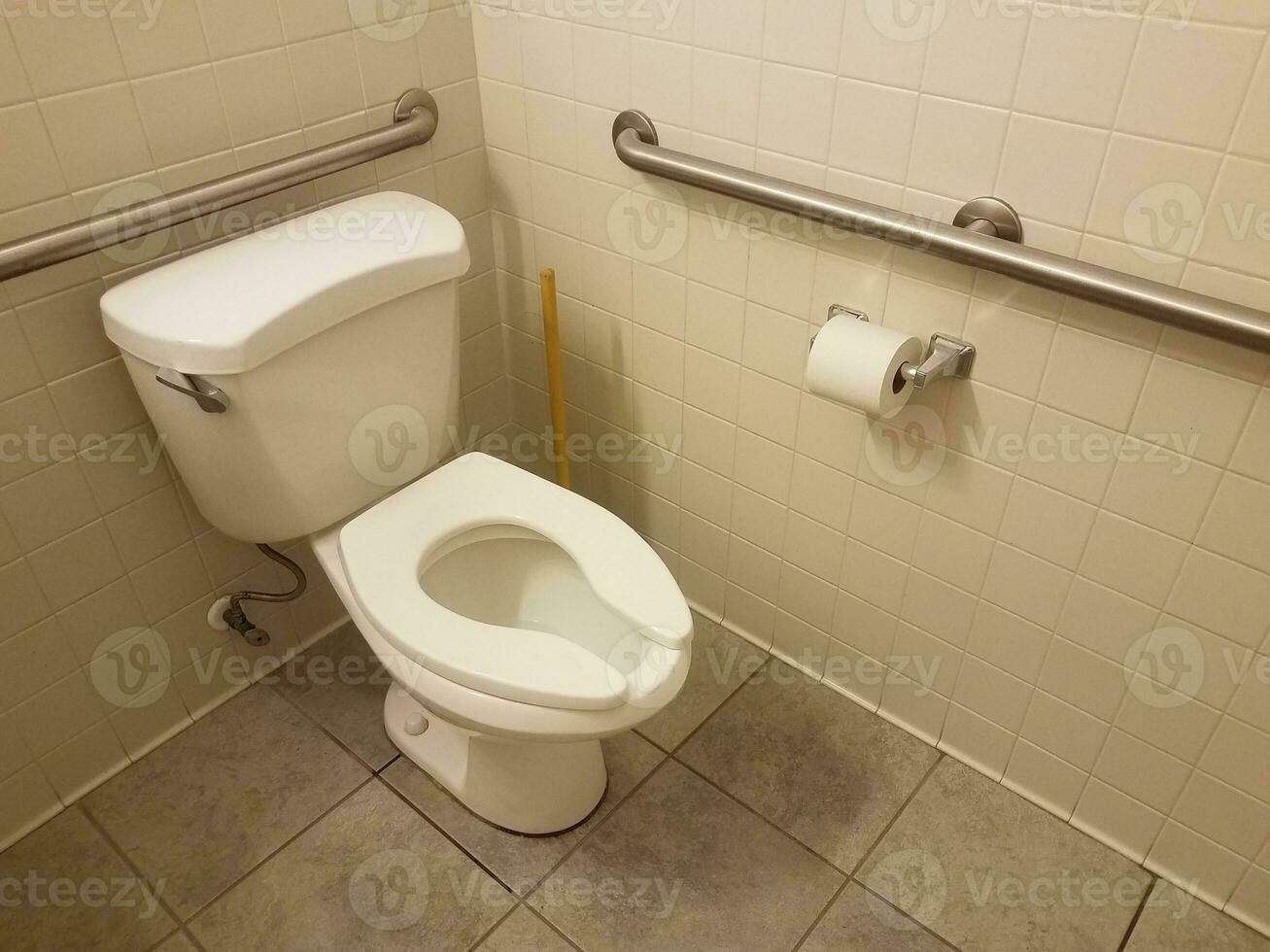WC bianco e piastrelle e stantuffo e carta igienica in bagno foto