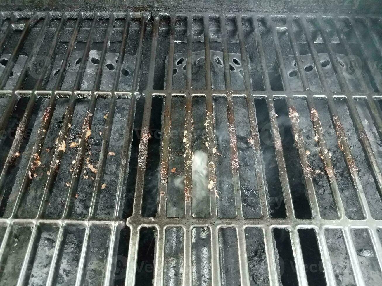 barre sporche o sporche sulla griglia del barbecue con fumo foto