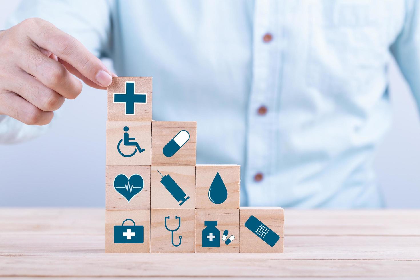 la mano sceglie un simbolo medico sanitario delle icone di emoticon sul blocco di legno, sul concetto di assicurazione sanitaria e medica foto