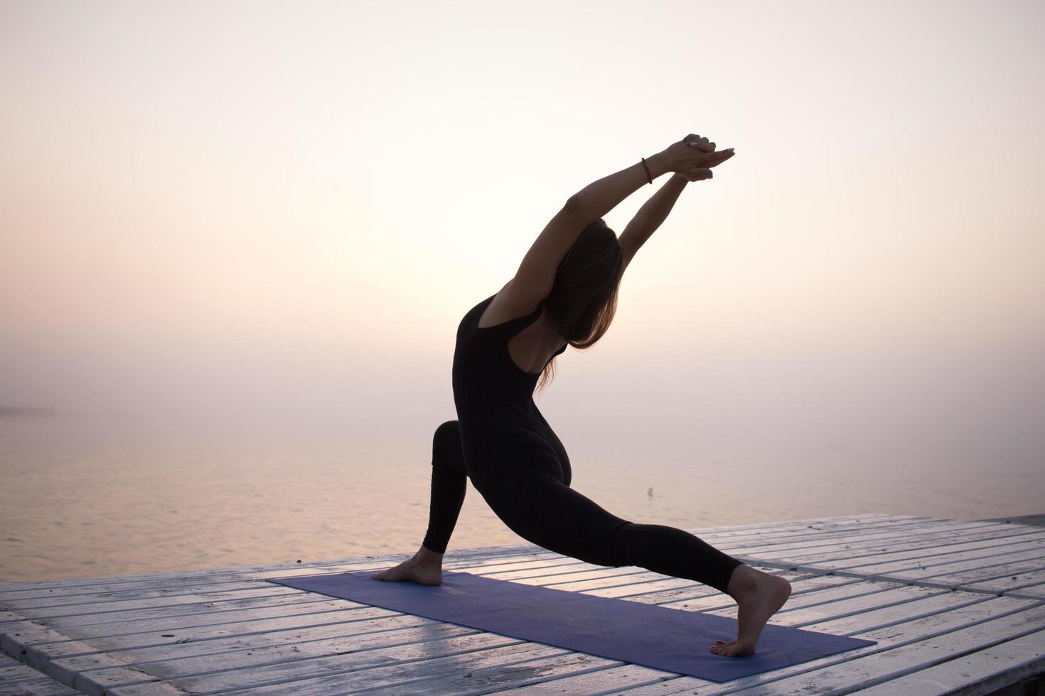 giovane donna in posa in asans yoga, sfondo del mare mattutino foto