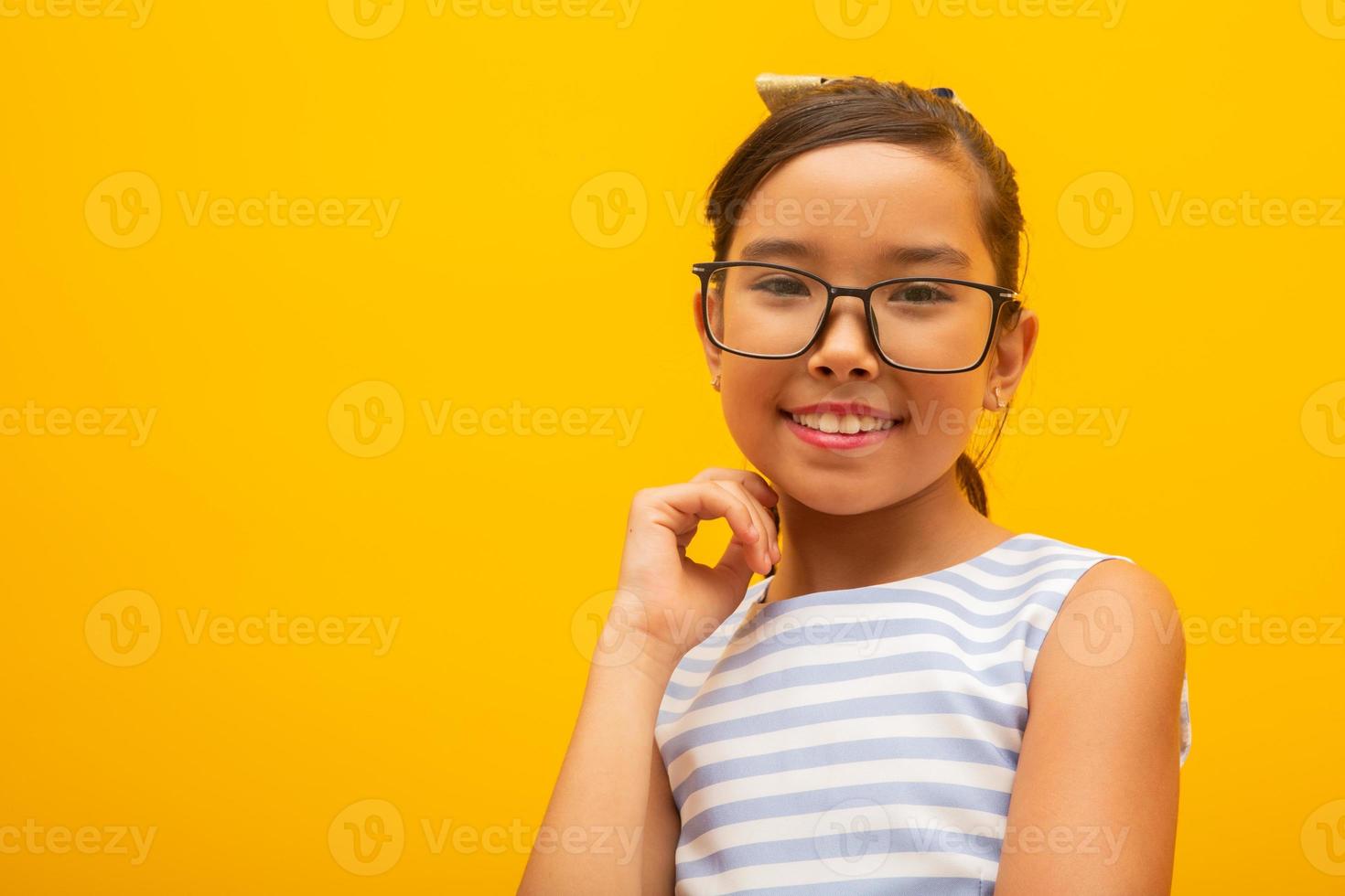 bella ragazza asiatica seduta su sfondo giallo. felice piccola ragazza asiatica sorridente. foto