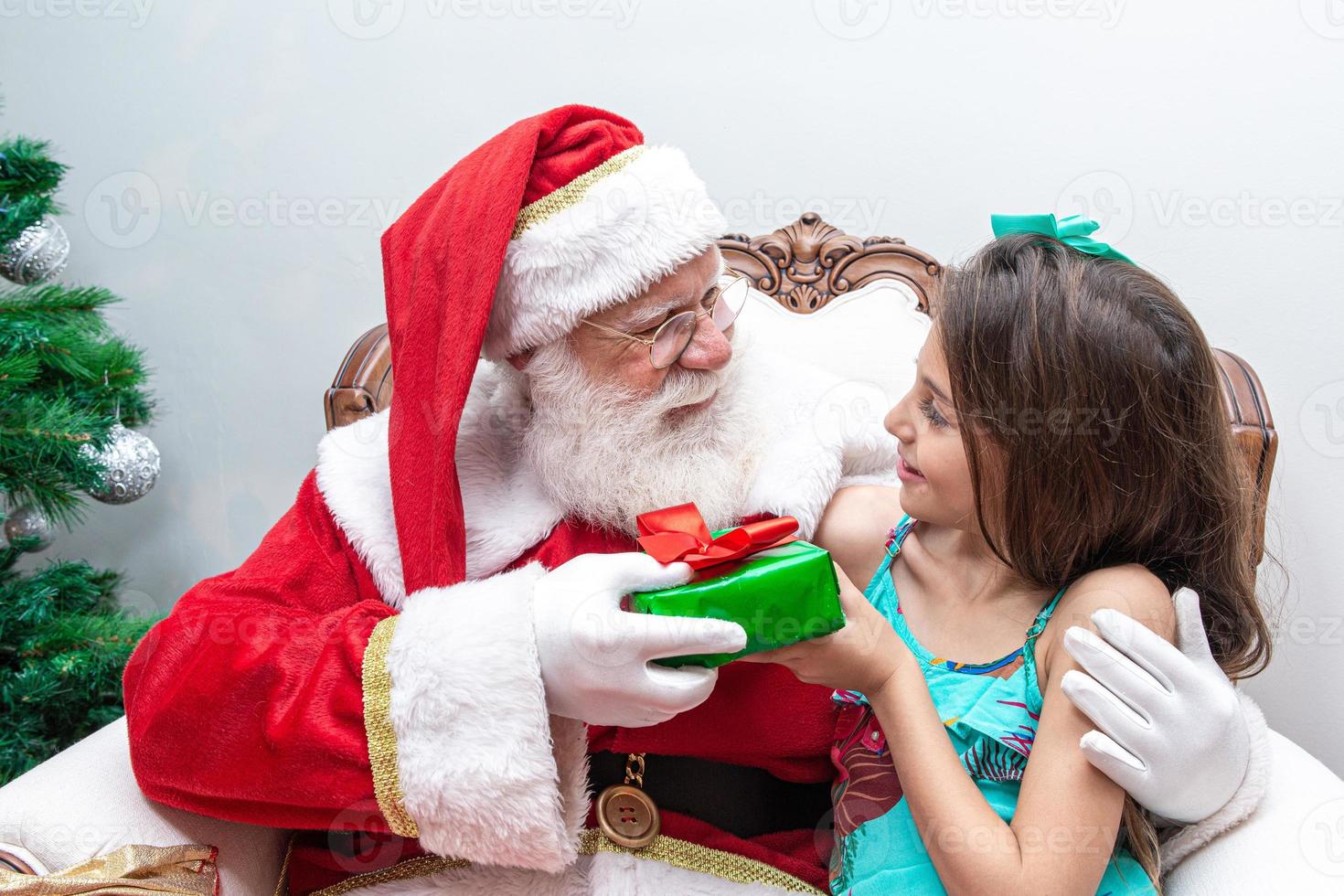 Babbo Natale consegna una confezione regalo a una bambina. vigilia di natale, consegna di regali. foto