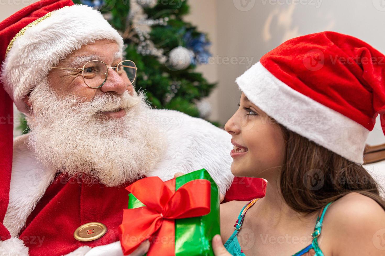 Babbo Natale consegna una confezione regalo a una bambina. vigilia di natale, consegna di regali. foto
