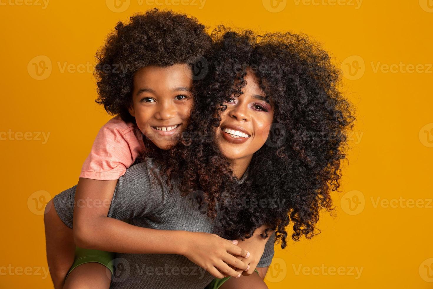 ritratto di giovane madre afroamericana con figlio bambino. sfondo giallo. famiglia brasiliana. foto