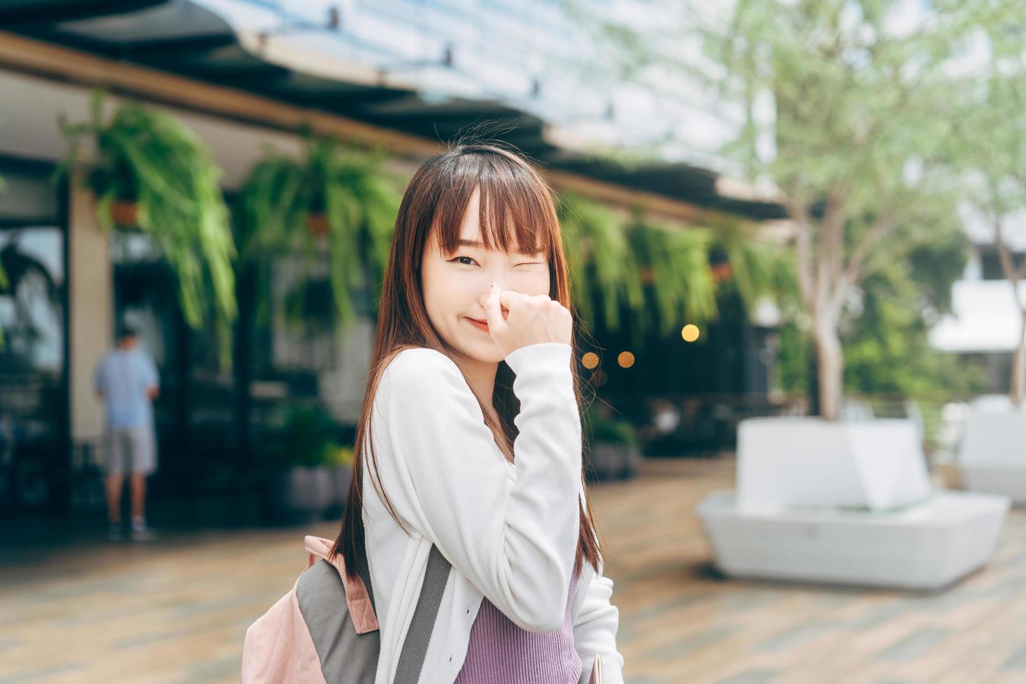 ritratto di giovane adulto asiatico studente donna capelli lunghi indossare zaino all'aperto. foto