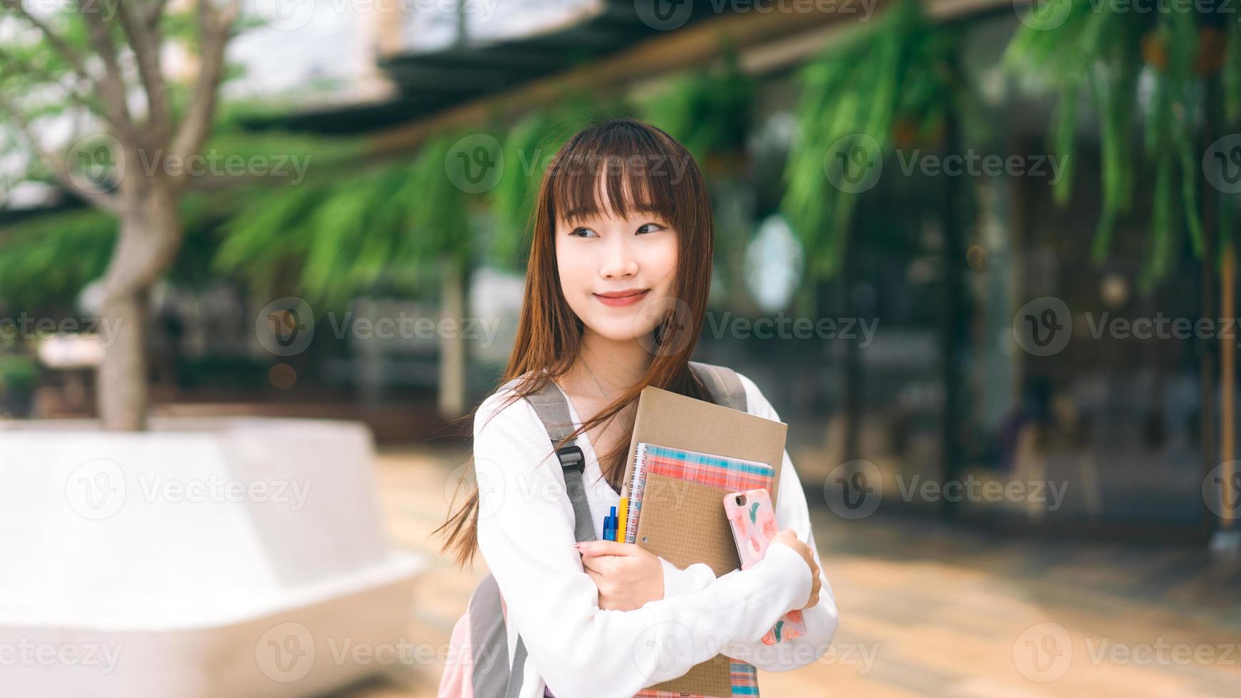 ritratto di giovane studente di college asiatico adulto donna con taccuino il giorno in città. foto