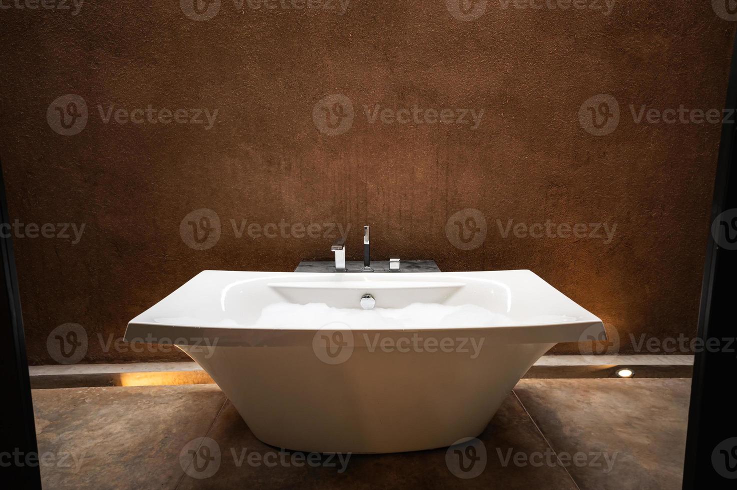 elegante vasca da bagno in ceramica bianca con bolla in bagno in terra naturale foto