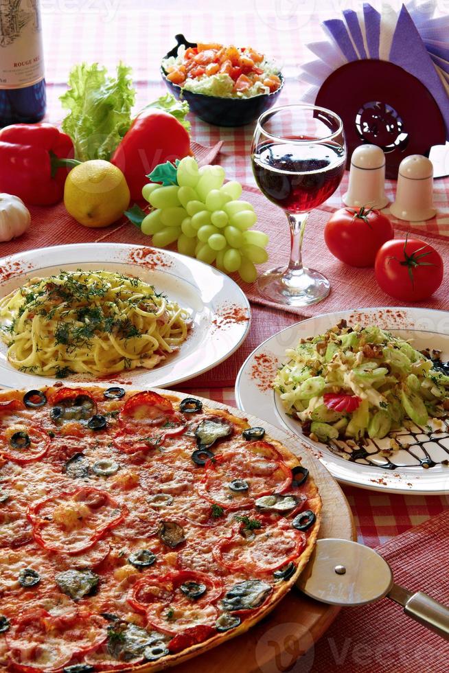 ambientazione classica italiana con pizza, pasta, insalata e vino foto