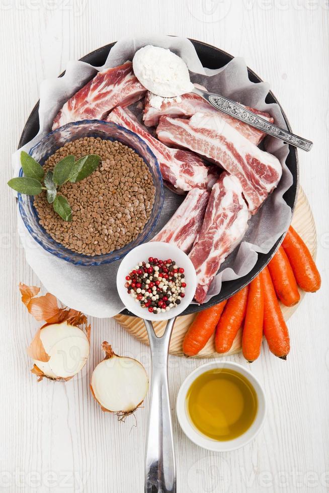 cottura degli ingredienti in padella: costine crude, lenticchie verdi, carote, foto