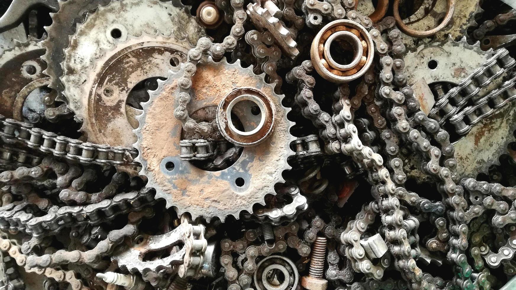 vecchie catene e ingranaggi di metallo rivestivano l'officina di riparazioni di biciclette con macchie nere di olio. foto