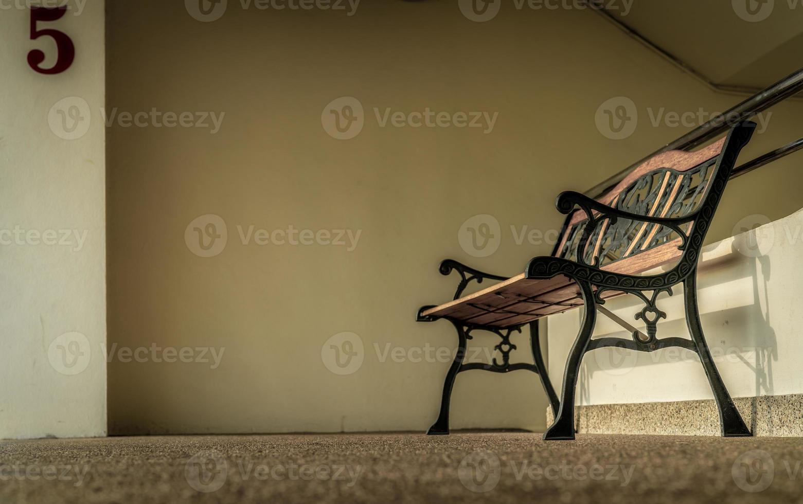 panca vuota in ferro battuto posta vicino alle scale dell'edificio. concetto depresso, triste e solitario. una panca vuota in ferro battuto. panca singola in condominio. concetto solitario. foto