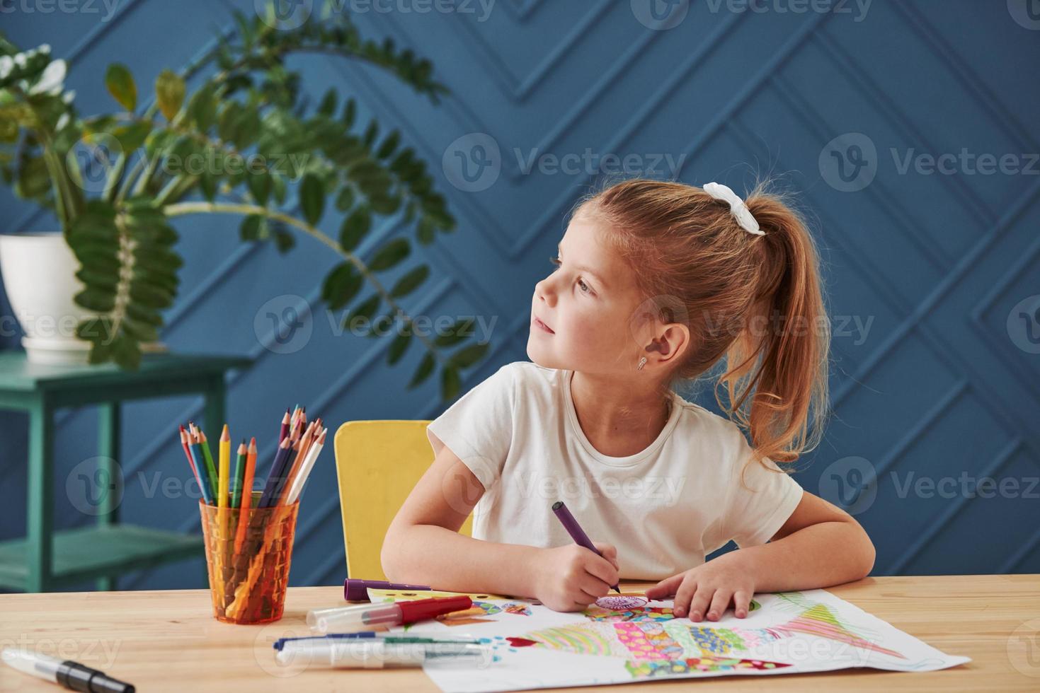 alla ricerca delle idee. la bambina carina della scuola d'arte disegna i suoi primi dipinti con matite e pennarelli foto