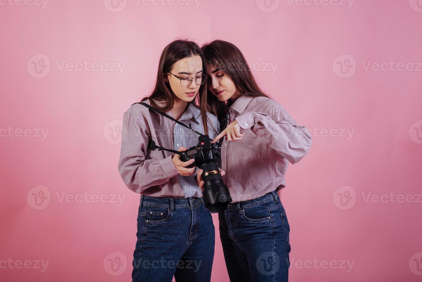 le ragazze padroneggiano l'arte della fotografia. due sorelle gemelle in piedi e in posa in studio con sfondo bianco foto