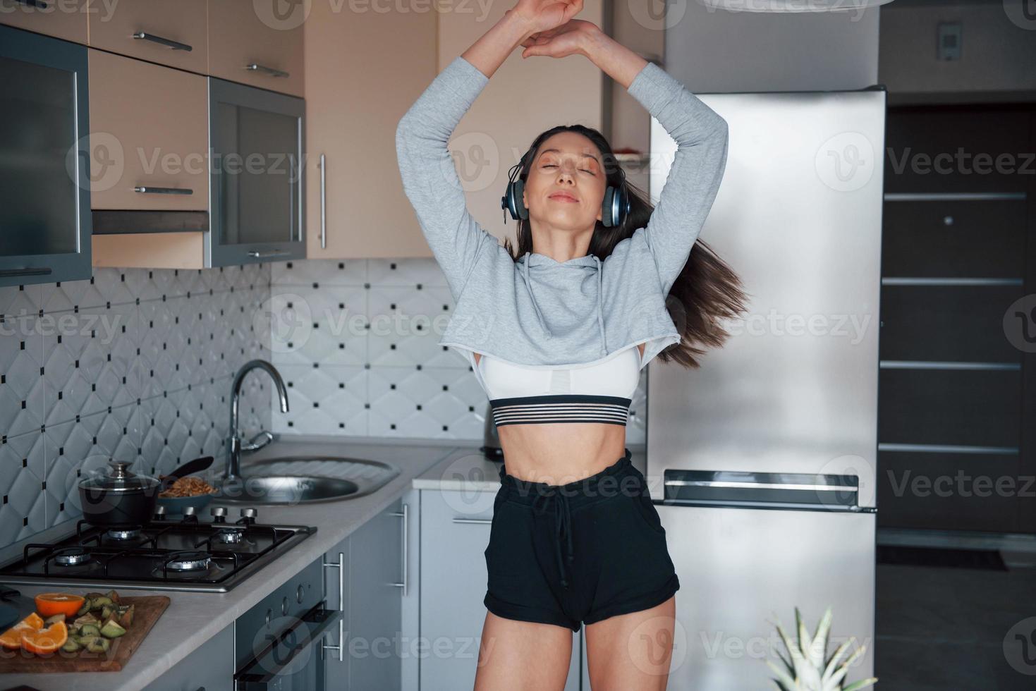 ballando a ritmo di musica. ragazza nella cucina moderna a casa nel suo fine settimana al mattino foto