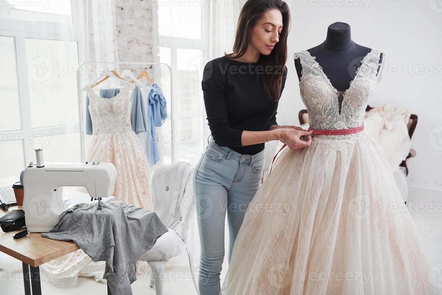 solo per assicurarsi che tutto sia a posto. stilista femminile lavora sui nuovi vestiti in officina foto