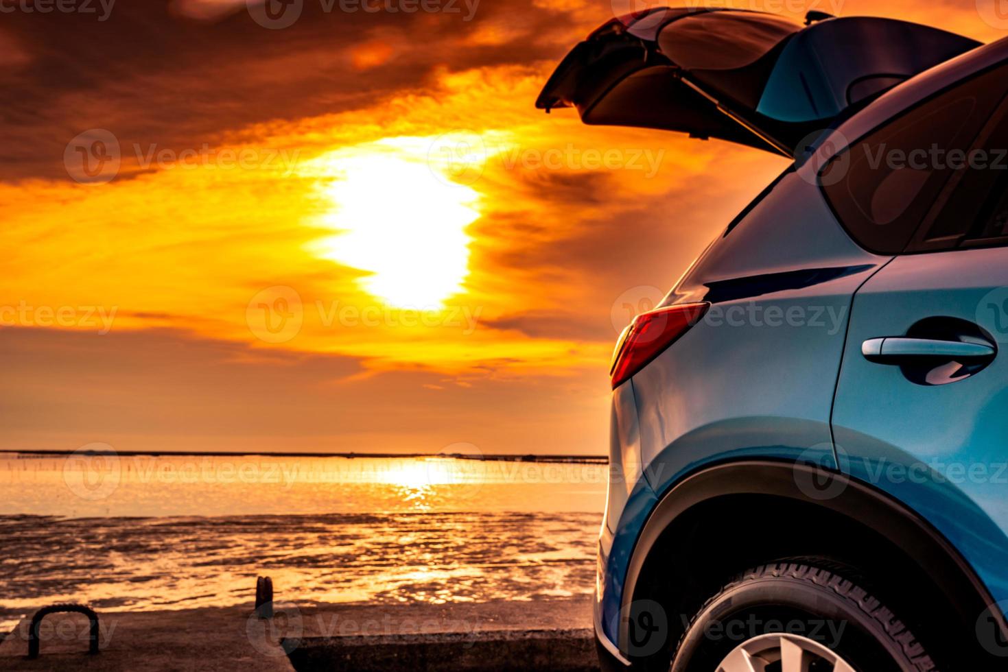 auto suv compatta blu con design sportivo e moderno parcheggiata su strada di cemento in riva al mare al tramonto. tecnologia rispettosa dell'ambiente. viaggio su strada viaggio in vacanza in spiaggia e camion aperto. foto