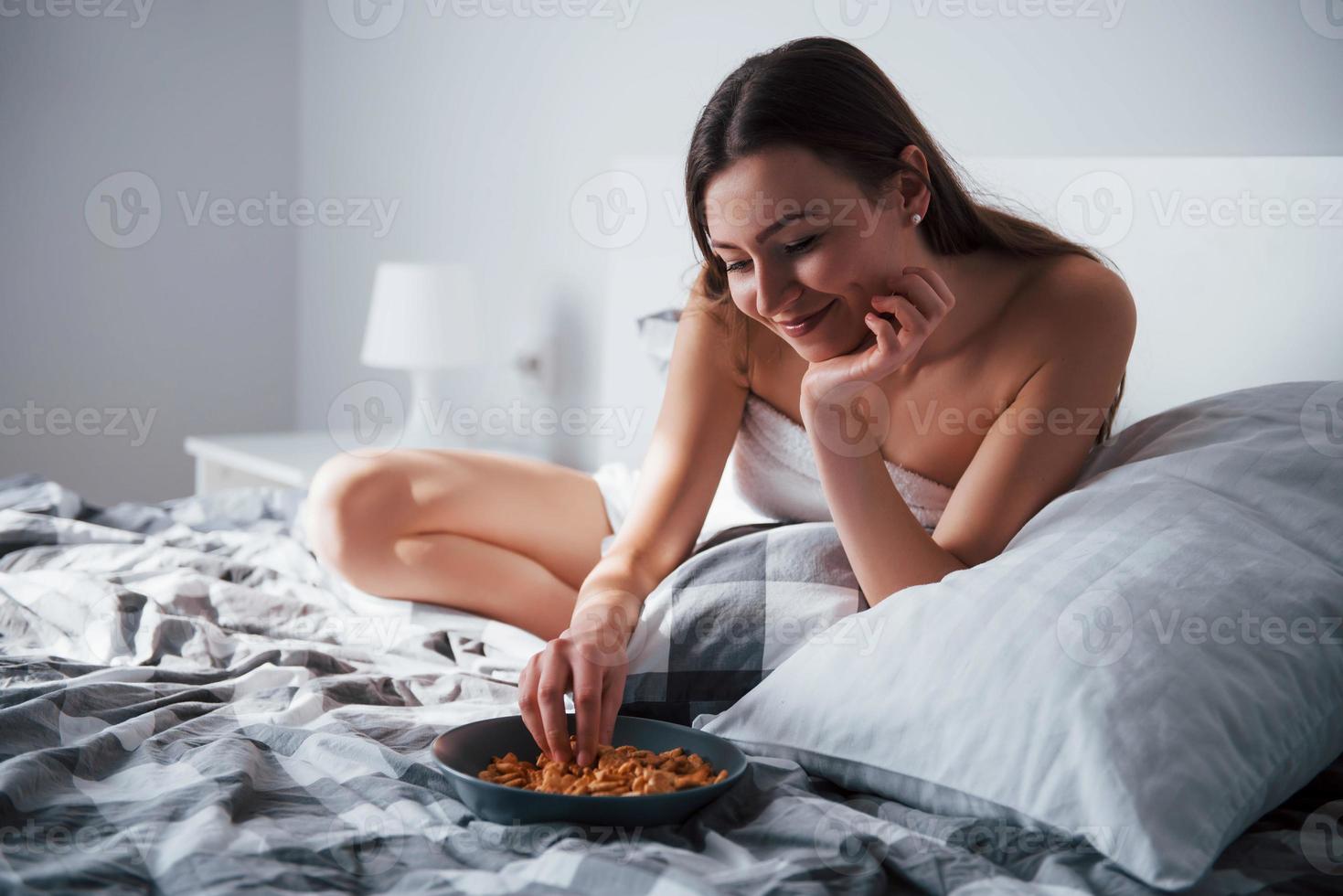 mangiando solo dei buoni biscotti. bella giovane donna sdraiata sul letto al mattino nella sua stanza foto