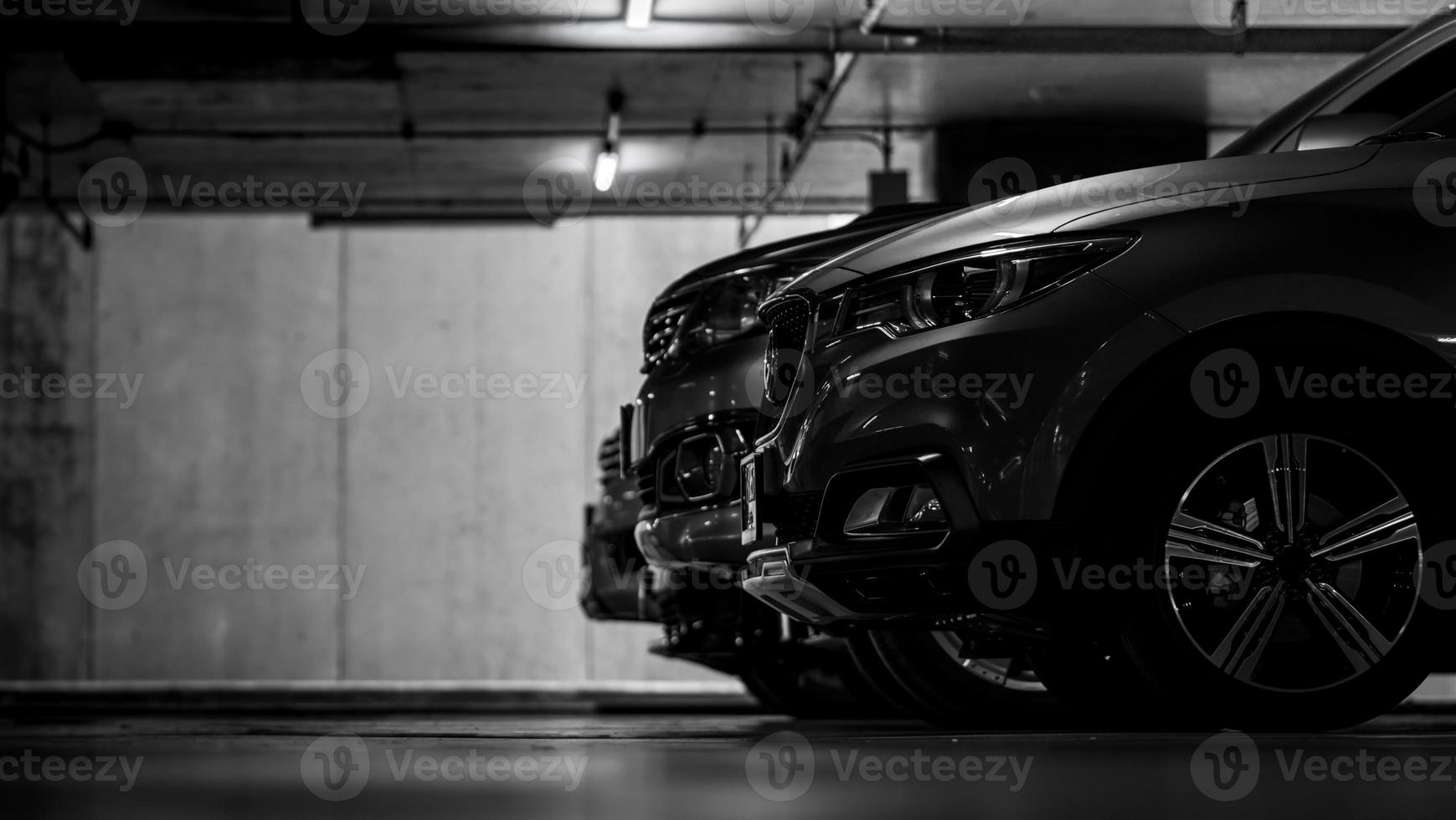 parcheggio auto nel parcheggio sotterraneo del centro commerciale. parcheggio auto coperto. scena in bianco e nero di un'auto parcheggiata nel seminterrato dell'edificio. vista laterale dell'auto suv parcheggiata in fila di notte. industria automobilistica. foto