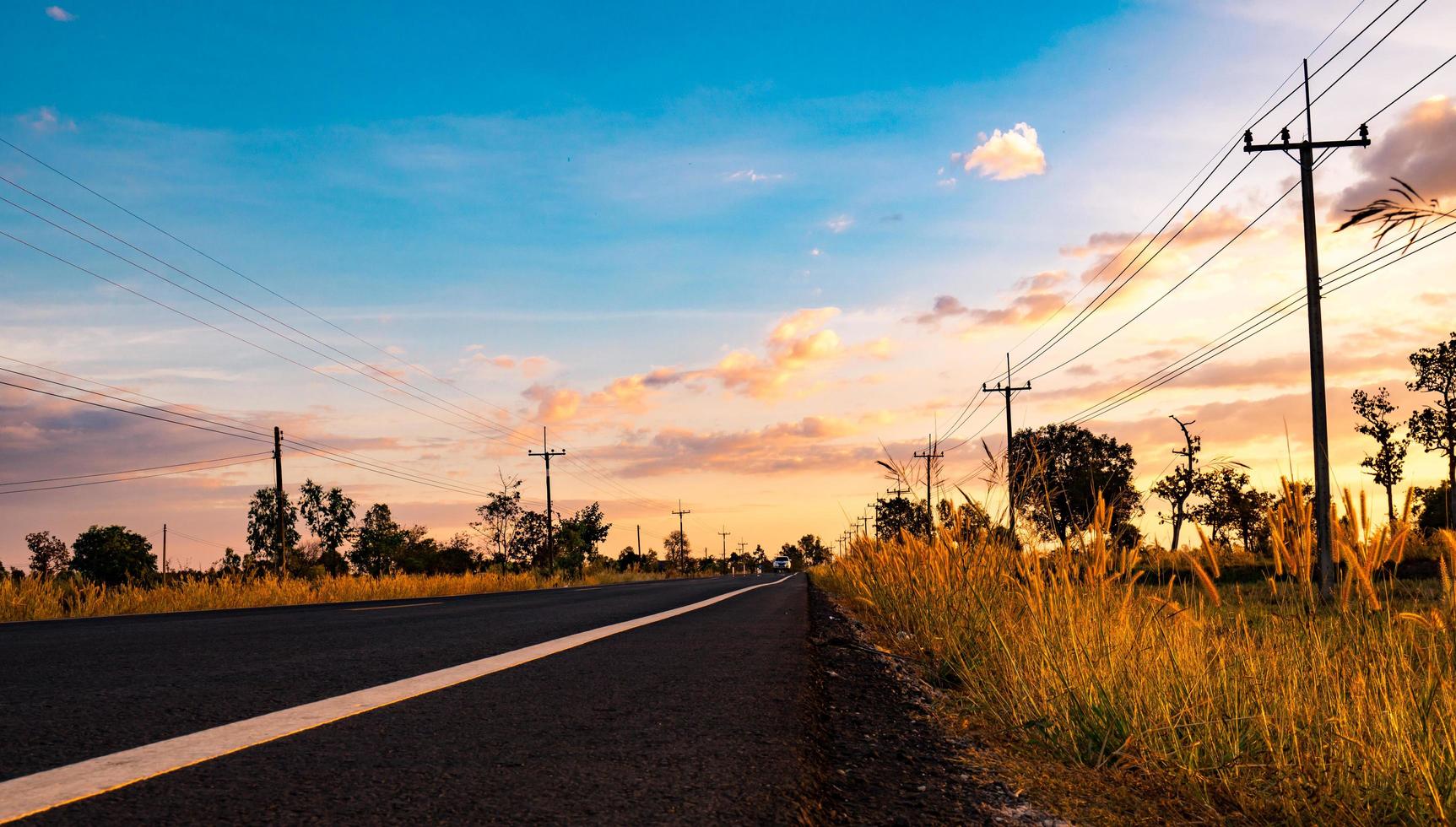 strada asfaltata con palo elettrico e prati lungo il percorso. campagna in tailandia foto