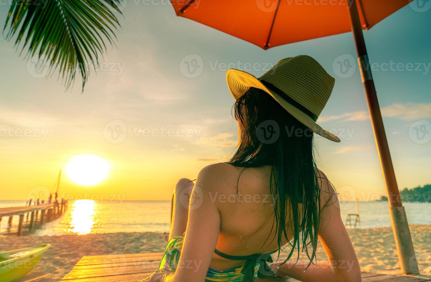 sexy, divertiti e rilassati donna caucasica indossare bikini sdraiato e prendere il sole sul lettino in spiaggia di sabbia all'isola tropicale paradiso sotto l'ombrellone al tramonto. vacanze estive al mare. viaggio di vacanza. foto